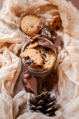Shortbread chocolate cookies and a glass of milk on a brown background.  Milk chocolate with nuts and cookies.