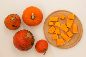 Orange pumpkins on a white background. Sliced pumpkin on a cutting board. Top view