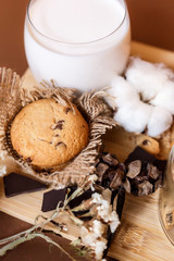 Shortbread chocolate cookies and a glass of milk on a brown background.  Milk chocolate with nuts and cookies.