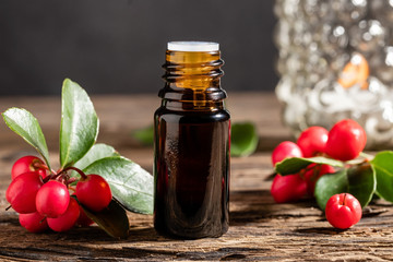 A bottle of essential oil with fresh wintergreen twigs