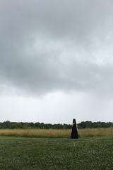 Fototapeta premium silhouette of woman in a field on a cloudy day