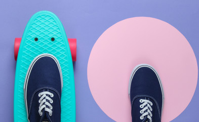 Cruiser board and sneakers on purple background with a pink pastel circle. Youth hipster concept....