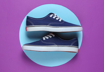 Sneaker in the middle of purple background with blue pastel circle. Youth hipster concept. Summer fun. Top view