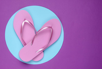 Pink flip flops on purple background with blue pastel circle. Minimalistic vacation on the beach concept. Summer time