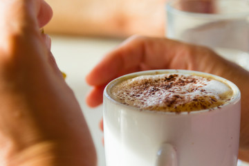 Hengistbury Head, Bournemouth, UK. Pair of hands wrapped around warm cup of coffee.