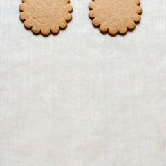 Background with two ginger cookies on baking paper, traditional Christmas treat. Text space, empty template.