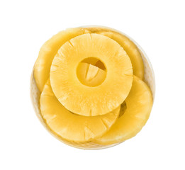 Bowl with slices of delicious sweet canned pineapple on white background, top view