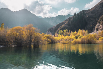 Beautiful autumn landscape. Mountains and lake, yellow trees in the reflection. Almaty, Kazakhstan