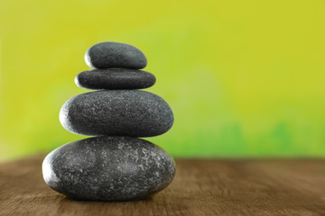 Stack of stones on table against blurred green background, space for text. Zen concept