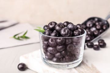 Glass of fresh acai berries on board, closeup. Space for text