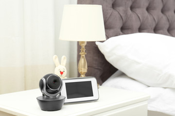 Baby monitor with camera and toy on table in bedroom, space for text. Video nanny