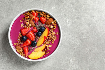 Delicious acai smoothie with granola and berries in bowl on grey table, top view. Space for text