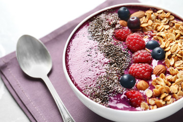 Delicious acai smoothie with granola and berries in bowl on table, closeup