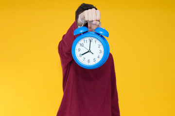 young man with alarm clock over color background