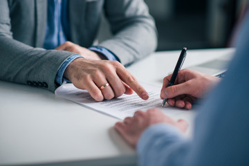 Close-up image of hand of bank broker showing a client where to sign signature in contract.