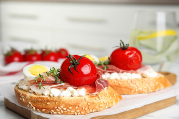 Cutting board of delicious bruschettas with prosciutto on white marble table