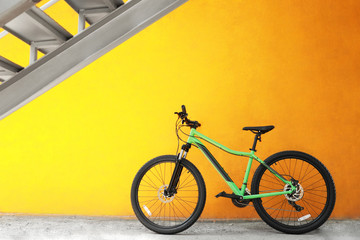 New modern color bicycle near yellow wall outdoors