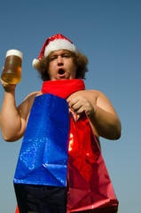 Obraz premium Funny Santa Claus is relaxing on the sea and drinking beer.