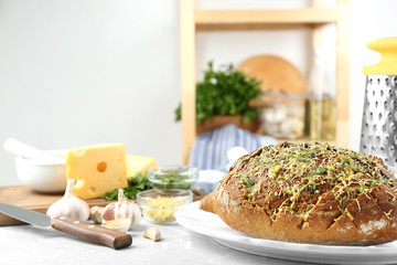 Tasty homemade garlic bread with cheese and herbs on grey table in kitchen. Space for text