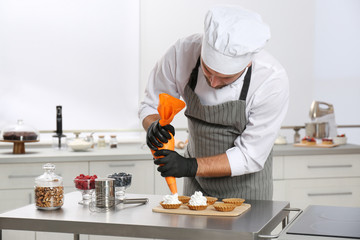 Pastry chef preparing desserts at table in kitchen