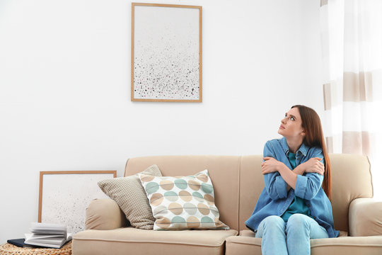 Young Woman Freezing Under Air Conditioner At Home