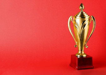 Golden trophy cup on red background. Space for text