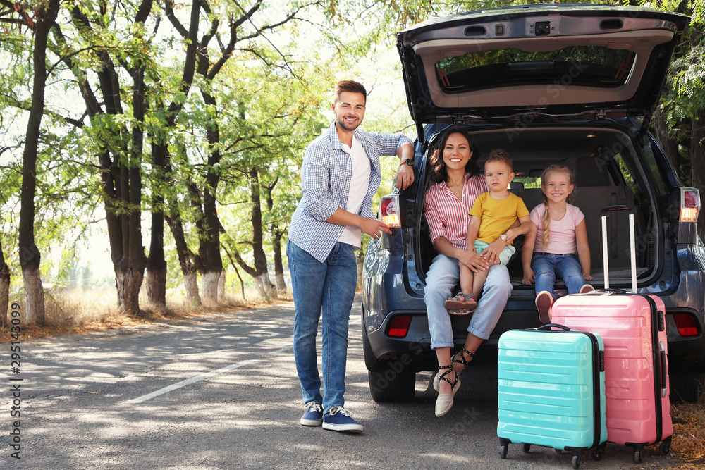 Wall mural happy family near car trunk on sunny day. road trip