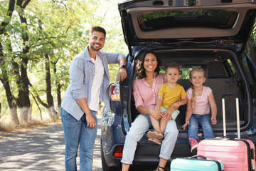 Happy family near car trunk on sunny day. Road trip