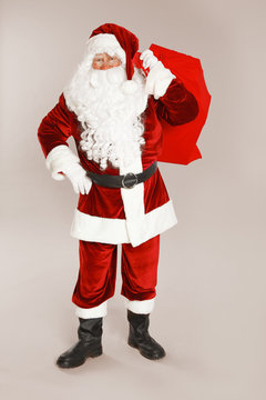 Authentic Santa Claus with bag full of gifts on grey background