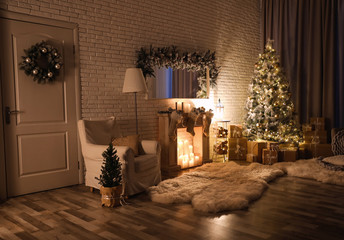 Stylish interior with beautiful Christmas tree and artificial fireplace at night