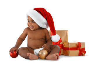 Cute African-American baby wearing Santa hat with Christmas gifts on white background