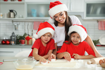 Happy family with Santa hats cooking in kitchen. Christmas time