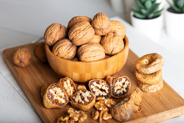 Whole walnuts in bowl. Dried figs with walnuts on wooden background.