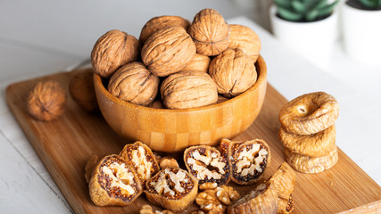 Whole walnuts in bowl. Dried figs with walnuts on wooden background.