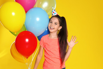 Fototapeta na wymiar Happy girl with balloons on yellow background. Birthday celebration