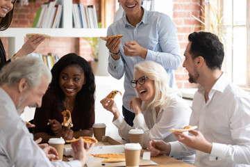 Happy diverse colleagues have lunch eating pizza together