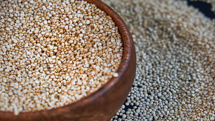 White quinoa seeds on a black background. quinoa in bowl on kitchen table top view. Healthy and diet superfood product.