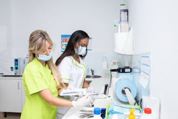 two dentists doctors in the sterilization room of a dental clinic. They are working sterilizing the...
