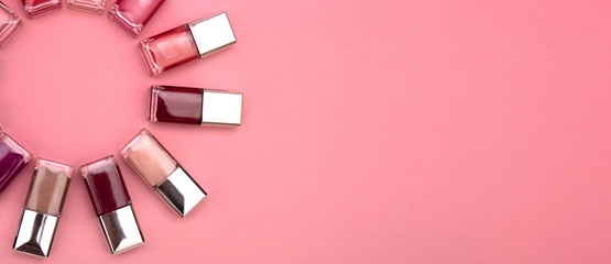 nail polishes of different colors are built on a pink background concept flat lay