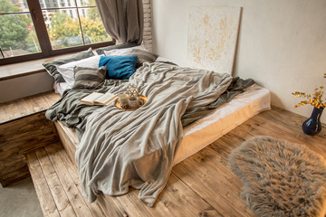 Bedroom in loft style and gray and blue colors. Wooden bed. Sleeping room interior