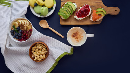 breakfast top view black background. oatmeal with berries, toasts on a wooden tray, nuts, coffee