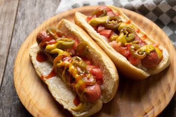 Hot dog with jalapeno pepper and tomato on wooden background