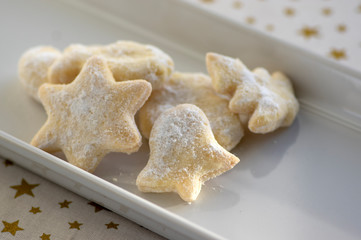 whipped cream delicious cookies with sugar icing on white ceramic plate, tablecloth with golden stars