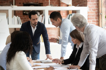 Diverse colleagues talk discussing ideas at meeting