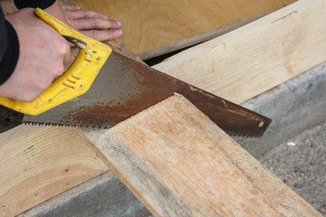 Fototapeta na wymiar Worker cuts a piece of wooden board. Carpentry work.