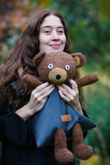 romantic fall outdoor portrait of woman with teddy bear bag in the park