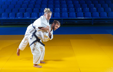 Martial arts. Sparing Portners. Sport man and woman in white kimono train judo throws and captures...
