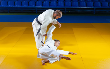 Martial arts. Sparing Portners. Sport man and woman in white kimono train judo throws and captures in the sports hall