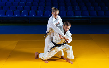 Martial arts. Sparing Portners. Sport man and woman in white kimono train judo throws and captures...