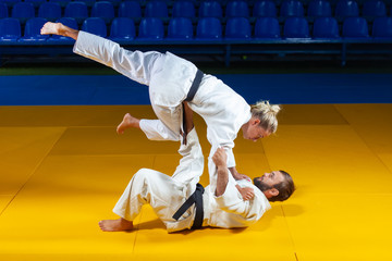 Martial arts. Sparing Portners. Sport man and woman in white kimono train judo throws and captures...
